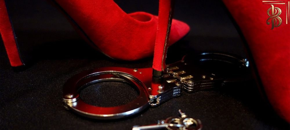 photo of a pair of handcuffs on the ground with a stiletto heel shoe on top