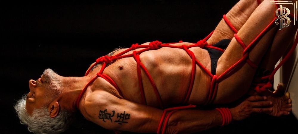 man in briefs tied with red rope