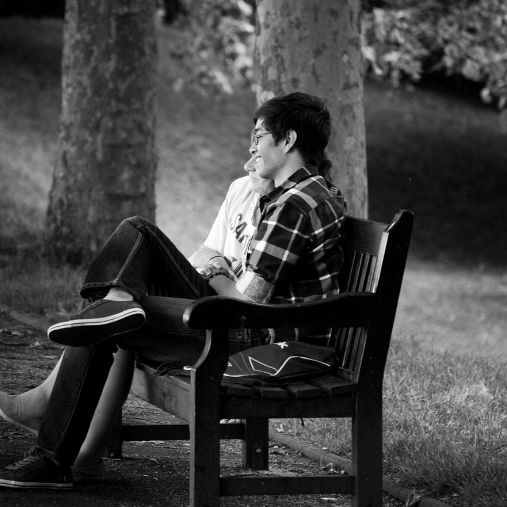 black and white photo of an amorous couple sitting on a bench