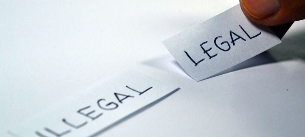 two pieces of paper on a table, one marked Illegal, the other Legal